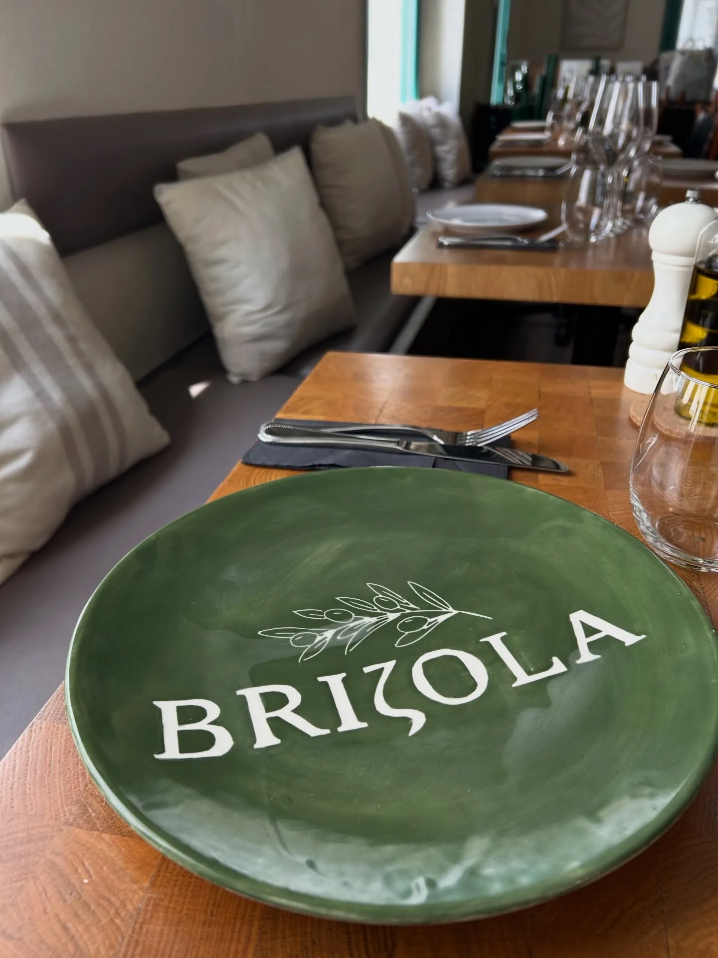 An olive-green ceramic plate hand-printed with the Brizola olive-branch wordmark