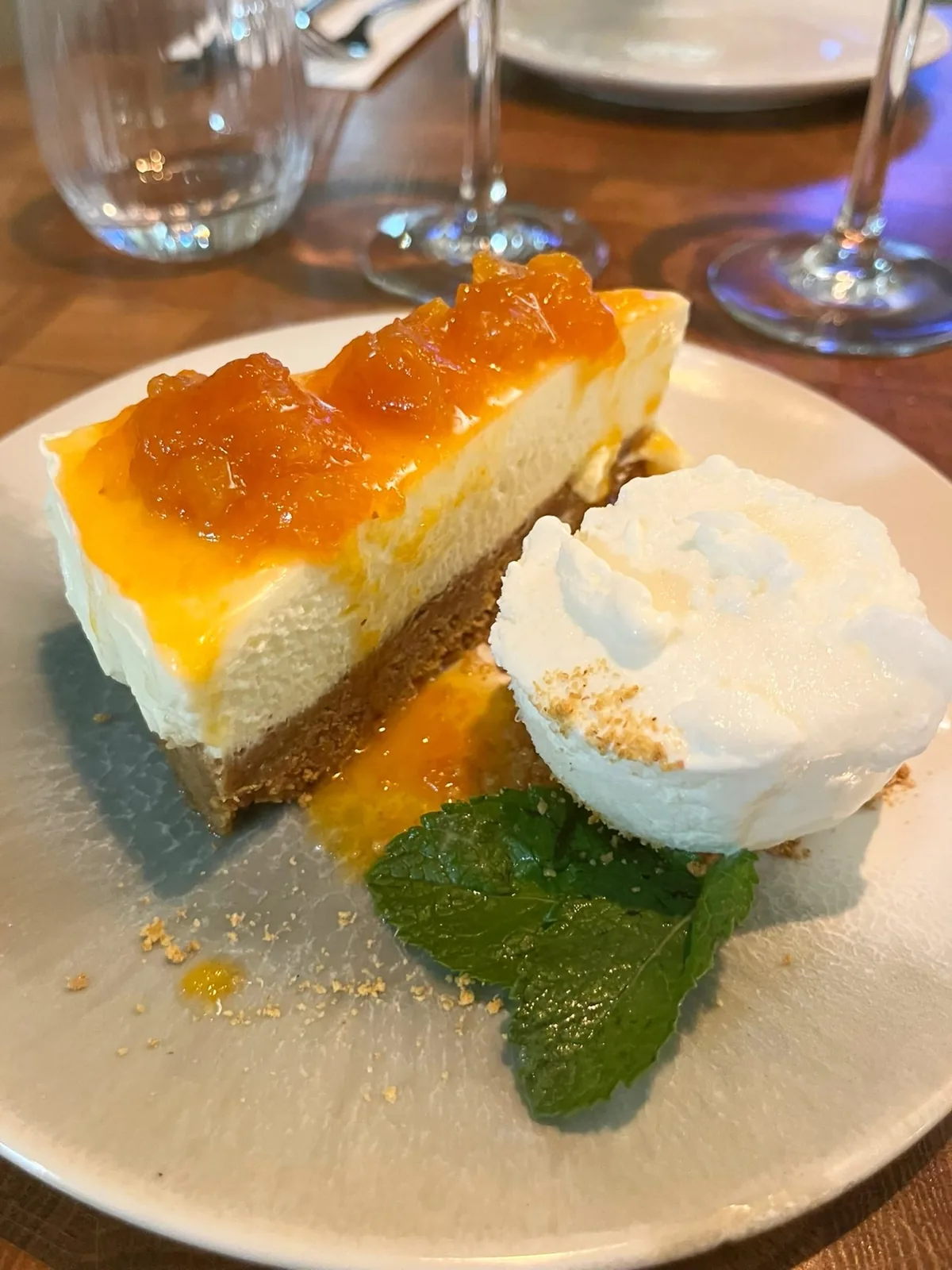 A slice of homemade cheesecake with orange marmalade, cream and mint