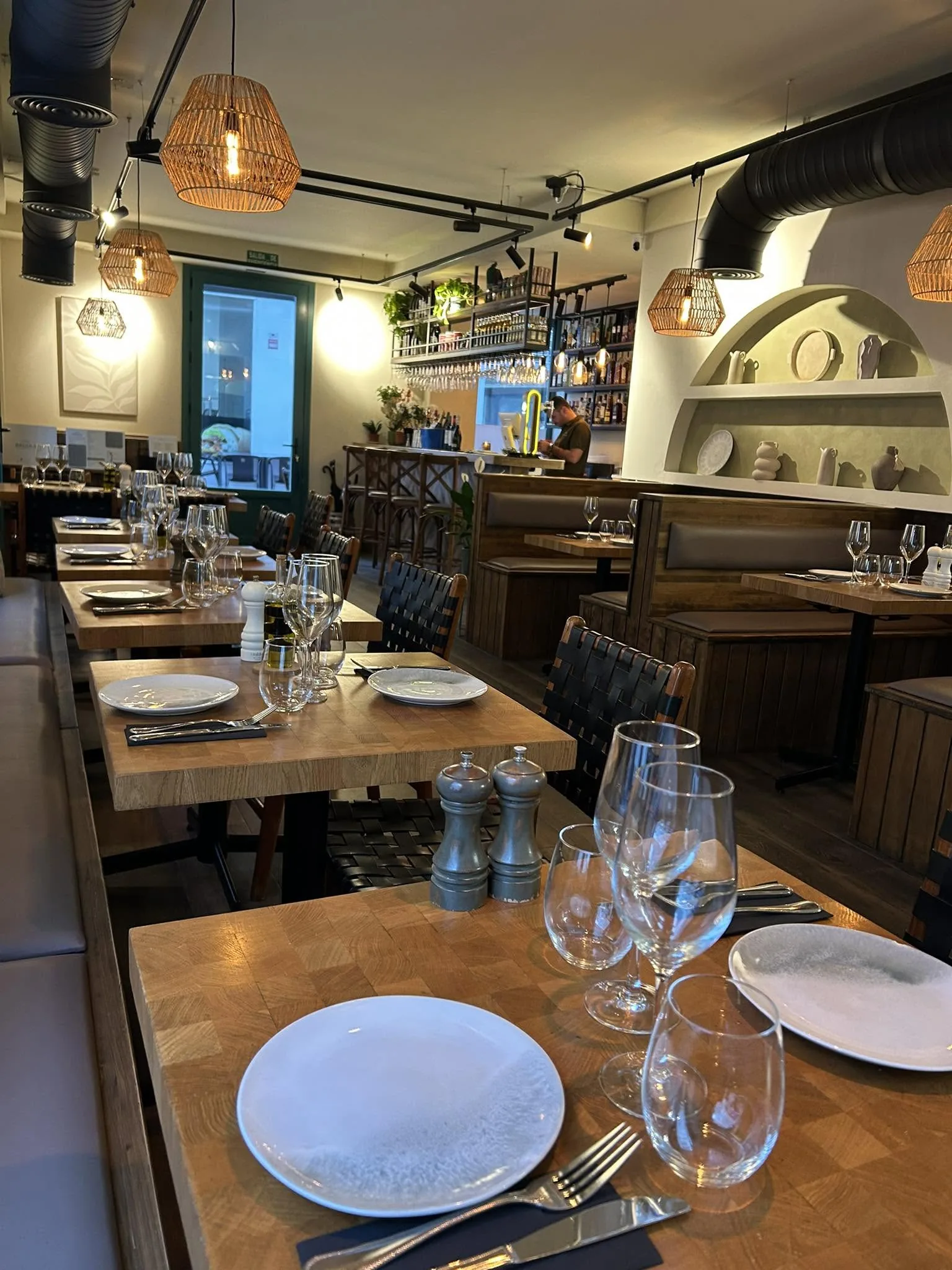 The Brizola dining room — oak tables, woven leather chairs, rattan pendants and the bar beyond