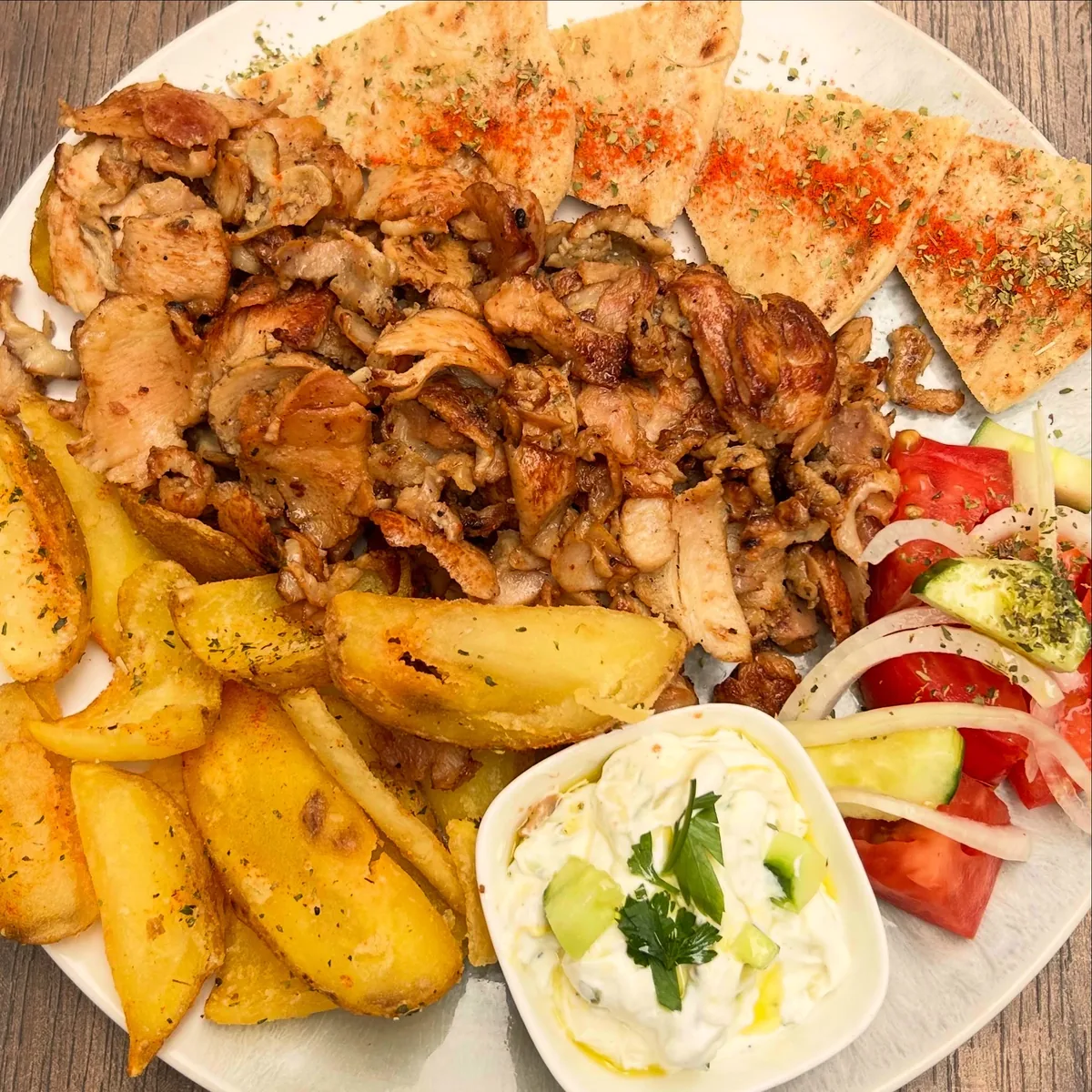 A gyros plate — chicken gyros with pitta, Greek village fries, tomato, onion and tzatziki