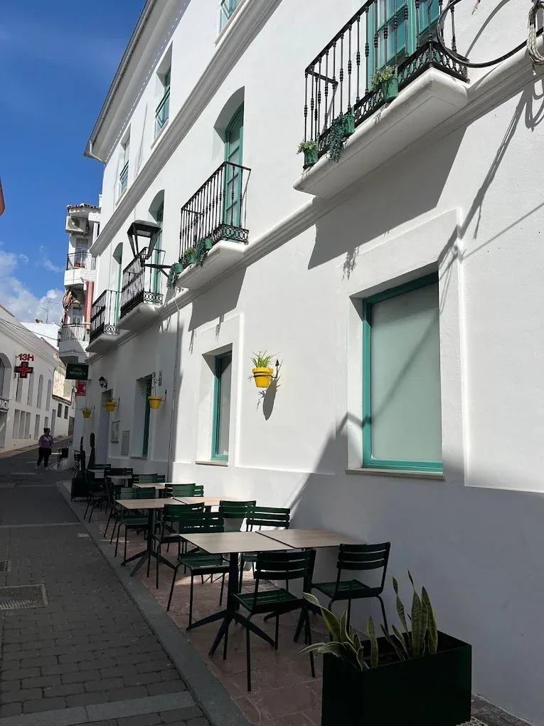 A whitewashed Estepona street with green shutters, hanging flowerpots and Brizola's olive-green terrace chairs